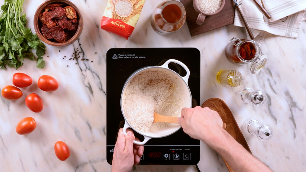 Refogue o arroz Saludães com alho e azeite antes de adicionar o caldo de tomate