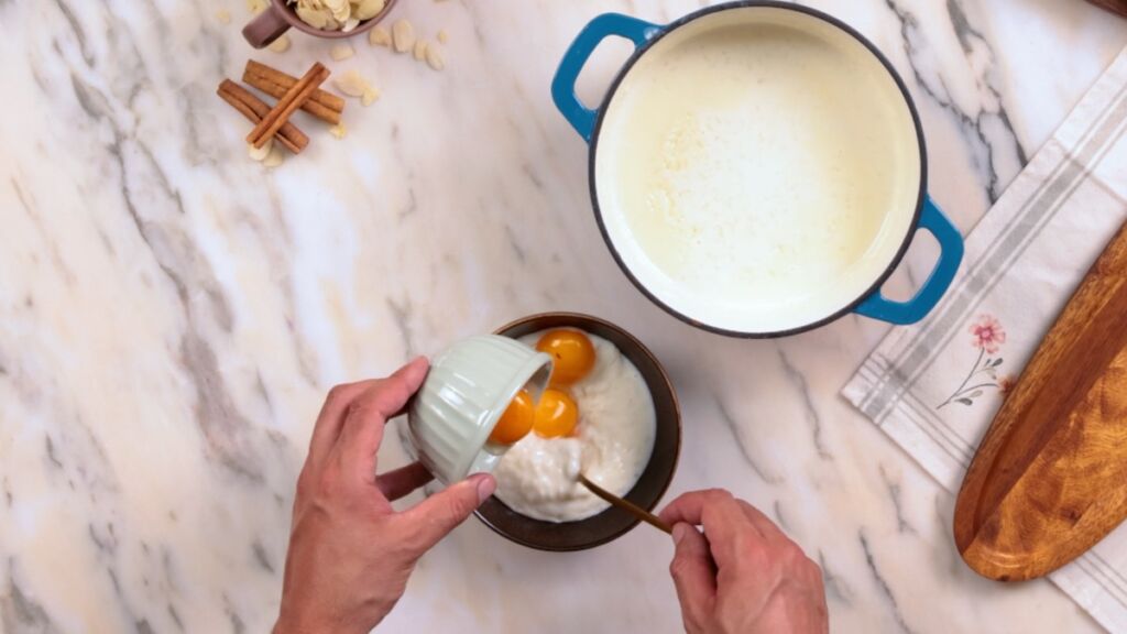 Numa taça, junte 5 colheres de sopa da mistura de arroz com as gemas para as temperar.