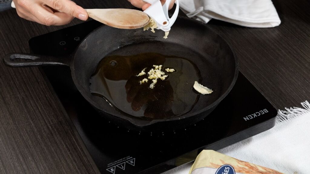 Num tacho, colocar um fio de azeite, o alho picado e alourar muito bem o frango de todos os lados.