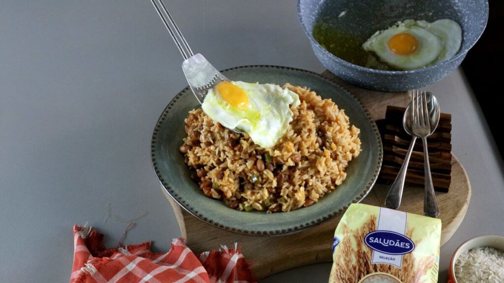 A apresentação do ovo sobre o arroz com feijão bem temperado cria um contraste visual e de sabores irresistíveis.