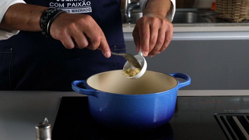 Num tacho aqueça o azeite, junte depois a cebola, os dentes de alho, a polpa de tomate e o pimento, envolva e deixe refogar bem.