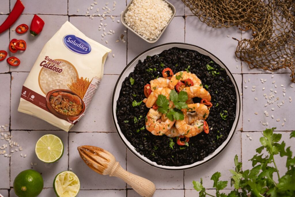 Sirva o arroz negro numa travessa, disponha o camarão salteado por cima e finalize com alguns coentros picados frescos, que não apenas adicionam cor, contrastando belamente com o negro do arroz